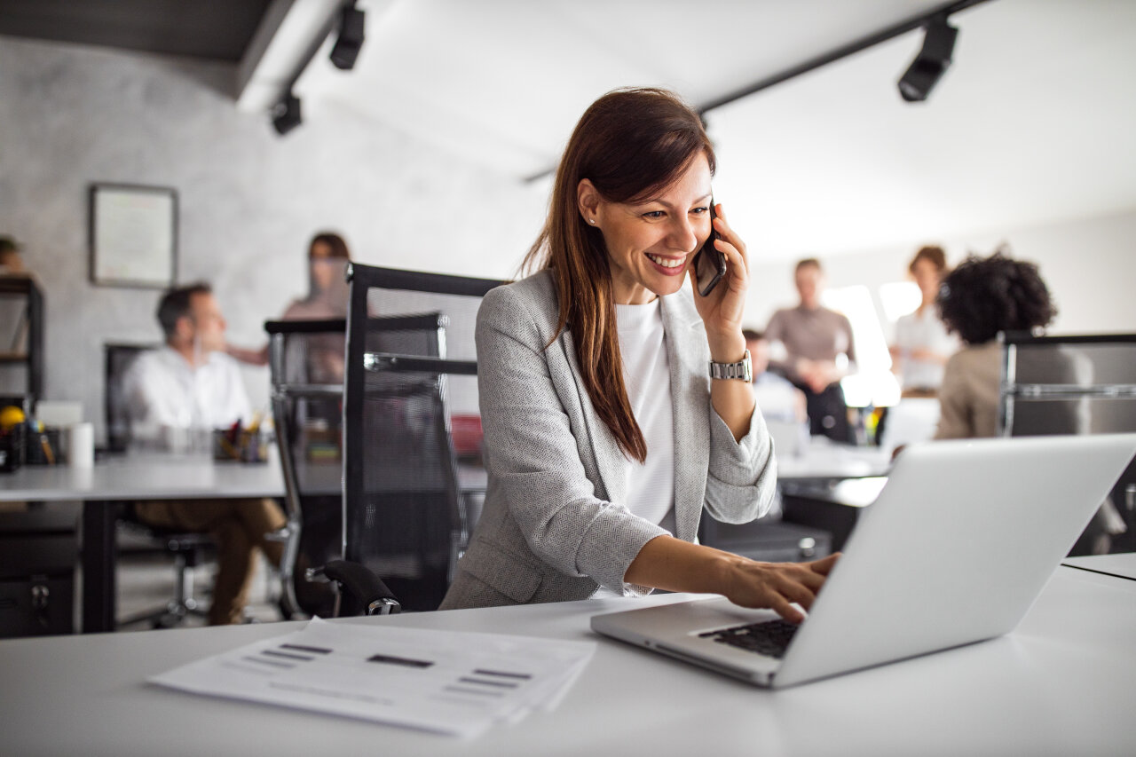 Frau telefoniert und arbeitet am Laptop in einem Büro